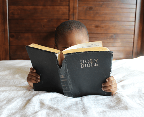 A small child reading the Bible
